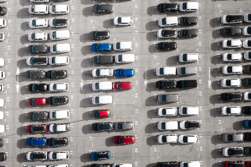 Vogelperspektive auf einen großen Parkplatz bei Gebrauchtwagen Ankauf Fulda, der mit Reihen weißer Autos gefüllt ist.